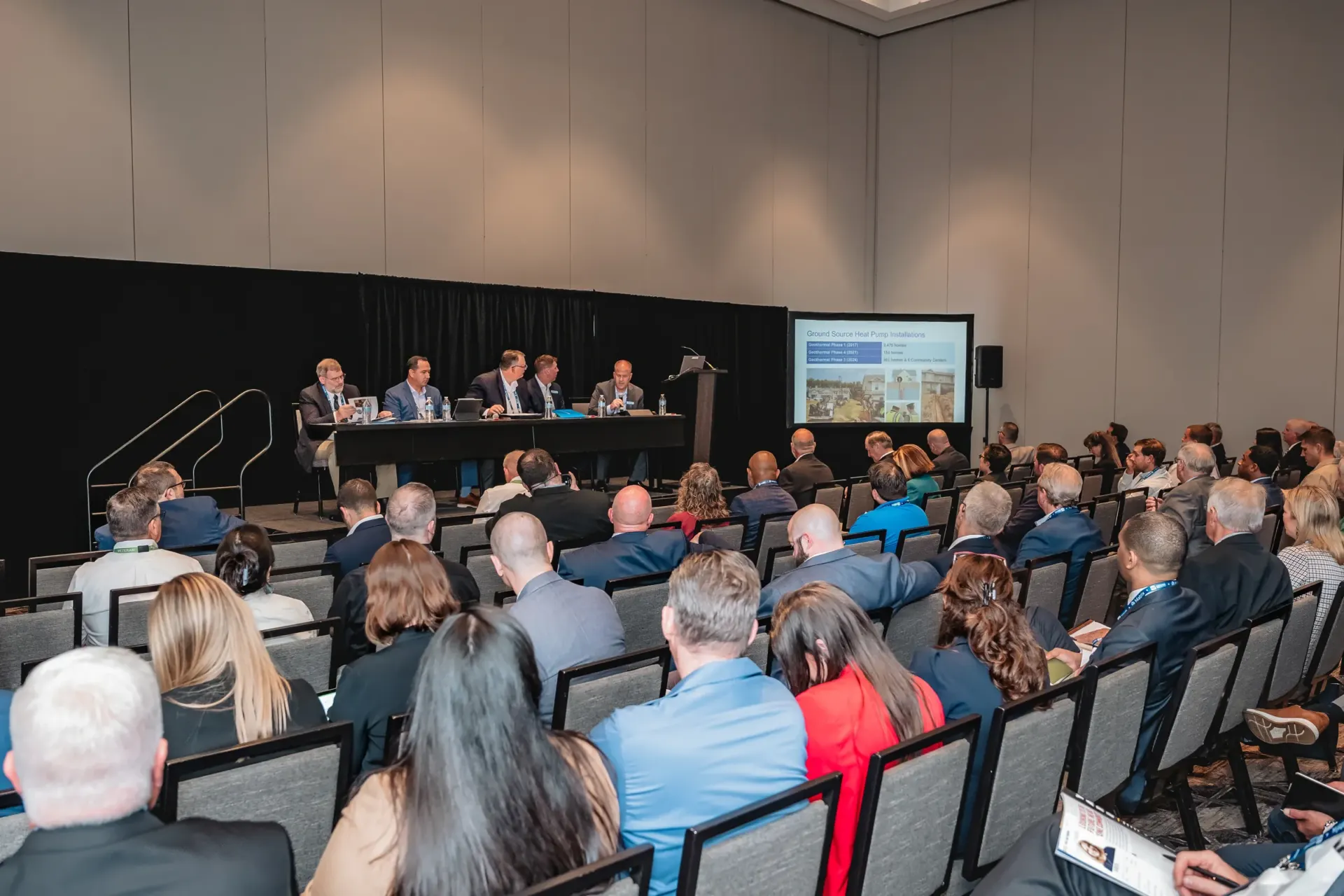 Panelists speak to an audience at a corporate conference.