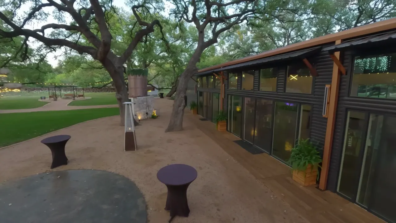 Aerial view of an event venue and patio beneath mature oak trees.