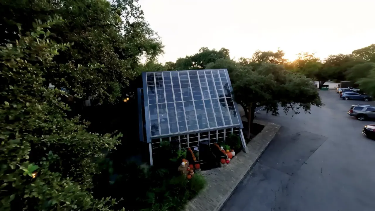 Elevated view of a glass-fronted building and parking area at sunset.