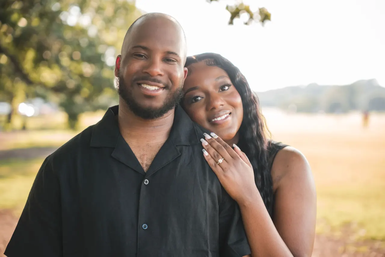 Engaged couple smiling together at sunset.