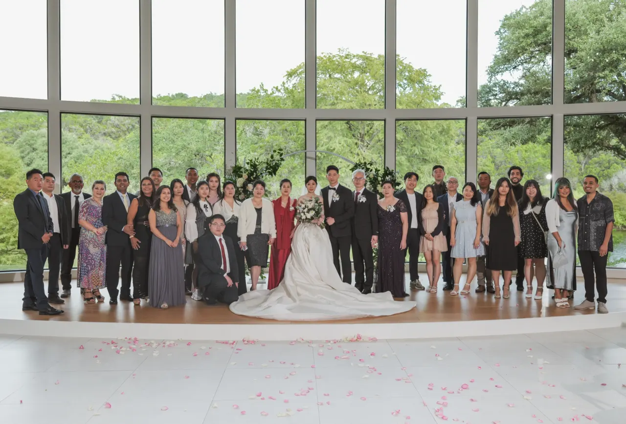 Wedding party gathers in a bright venue with tall windows.
